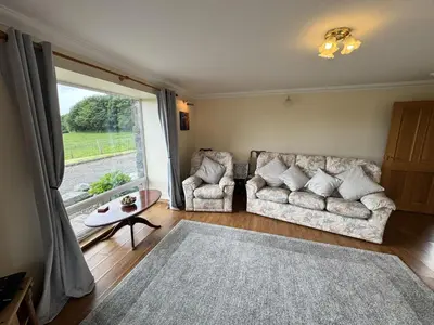 a living room with two couches and a large window at Wee Newton in Twynholm