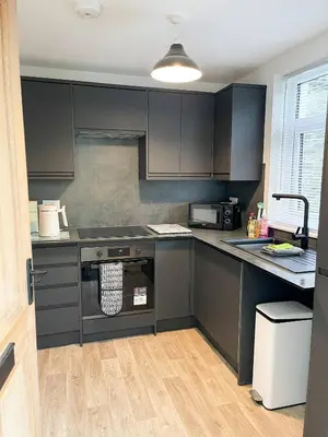 a kitchen with dark gray cabinets and a sink at The Retreat, Cosy 1 Bed Cottage, Town Centre Location in Kirkcudbright