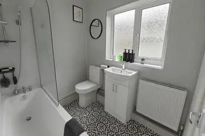a bathroom with a toilet and a sink and a tub at Coastal Haven - Steps From Beach in Whitehaven