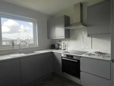 a kitchen with white cabinets and a sink and a window at Skiddaw Heights in Keswick