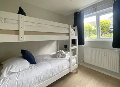 a bedroom with white bunk beds and a window at Skiddaw Heights in Keswick