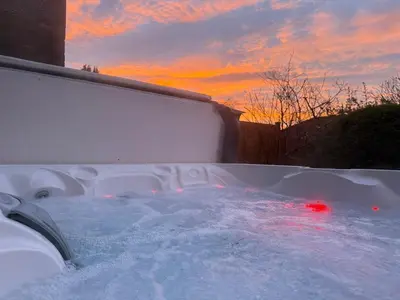 a hot tub covered in snow with a sunset in the background at Skiddaw Heights in Keswick