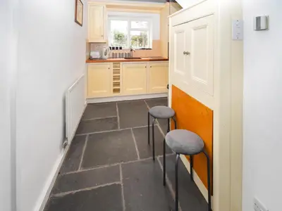 a small kitchen with two stools and a counter at Hideaway Cottage in Keswick