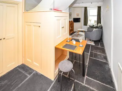 a kitchen with a table and a living room at Hideaway Cottage in Keswick