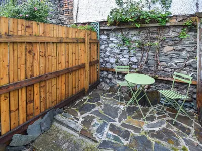 a patio with a table and chairs and a fence at Hideaway Cottage in Keswick