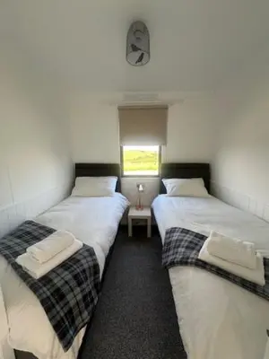 two twin beds in a room with a window at Bowmore 7 - Stunning Sea Views, Farm Stay in Stranraer