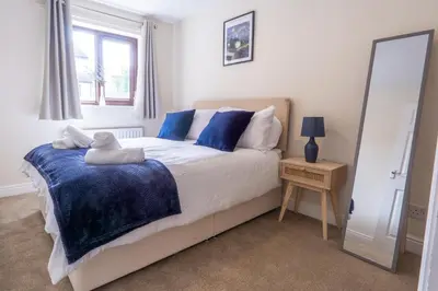 a bedroom with a bed with blue pillows and a mirror at 2 Bed, Ground Floor Flat, Carlisle in Carlisle