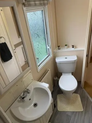 a bathroom with a toilet and a sink and a window at The West Lakes Caravan in Lamplugh