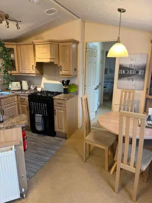 a kitchen with wooden cabinets and a table and chairs at The West Lakes Caravan in Lamplugh
