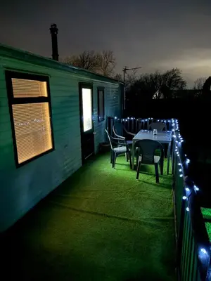 a patio with a table and chairs and lights at The West Lakes Caravan in Lamplugh
