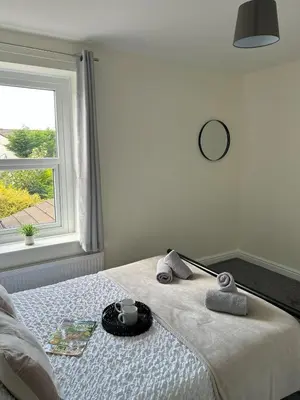a bedroom with a bed with towels and a window at Birks Terrace - 2 Bedroom - Sleeps 4 in Cleator Moor