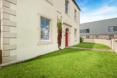 a house with a green yard next to a building at 2 Bed in Cockermouth oc-m32942 in Cockermouth