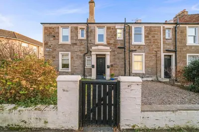 a brick house with a black gate in front of it at Couples or Golfers Near to Beach in Troon