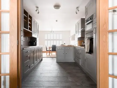a kitchen with white cabinets and a tile floor at Richmond, Tithebarn St, Keswick in Keswick