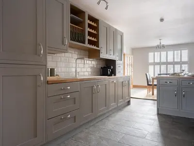 a large kitchen with white cabinets and a table at Richmond, Tithebarn St, Keswick in Keswick