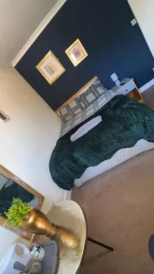 a bedroom with a large bed with a green blanket at QueensBerry accommodation in Annan