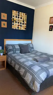 a bed in a bedroom with a blue wall at QueensBerry accommodation in Annan