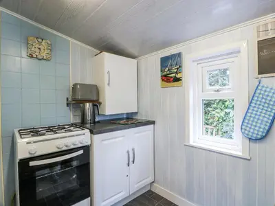 a kitchen with a stove and white cabinets and a window at Learig Lodge in Girvan