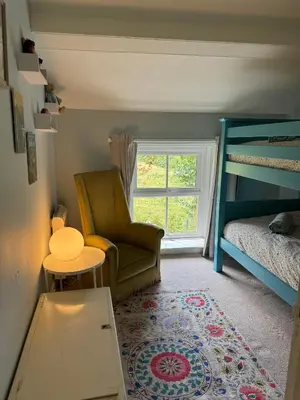 a bedroom with a chair and a bed and a window at 1 Laithes Cottages in Skelton