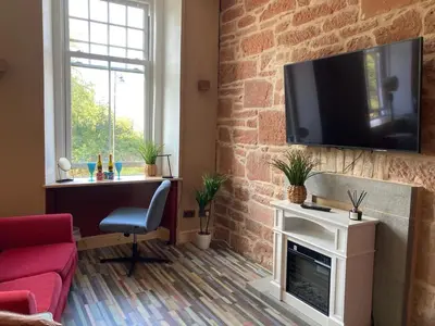 a living room with a fireplace and a tv on a brick wall at The Tartan Sheep in Kilmarnock