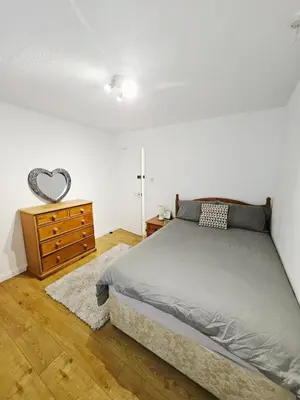 a bedroom with a bed and a dresser with a heart mirror at Egremont 2-Bed Flat Near Lake District with Free Parking & Wi-Fi in Egremont