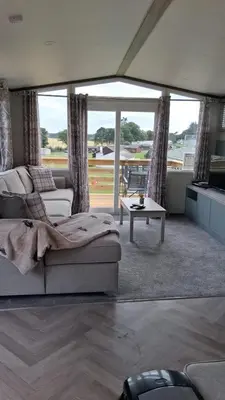 a living room with a couch and a table at Three Lochs Holiday Park- Lochwood Caravan in Newton Stewart