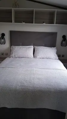 a large bed with two white pillows on it at Three Lochs Holiday Park- Lochwood Caravan in Newton Stewart