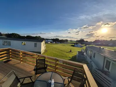 a deck with chairs and a view of a field at Three Lochs Holiday Park- Lochwood Caravan in Newton Stewart