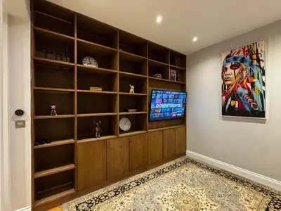 a living room with a tv and shelves at The Victorian Residence in Moffat