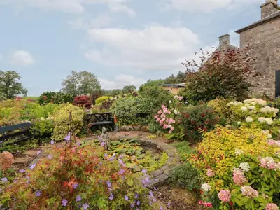 a garden with flowers and a bench in the middle at Balsaggart Farm in Maybole