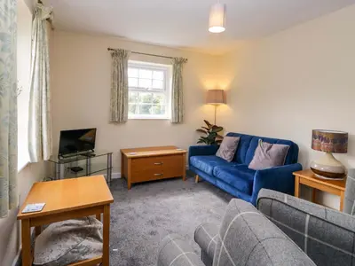 a living room with a blue couch and a tv at Buckbarrow in Seascale