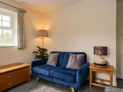 a blue couch in a living room with a lamp at Buckbarrow in Seascale
