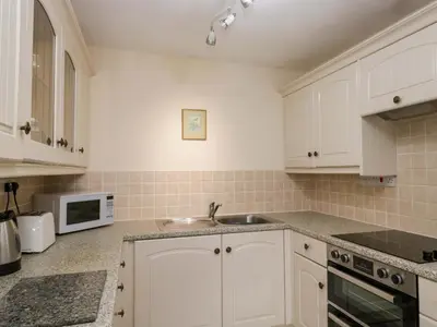 a kitchen with white cabinets and a sink and a microwave at Buckbarrow in Seascale