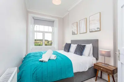 a bedroom with a large bed with a blue blanket at The Bay Suite - Donnini Apartments in Troon