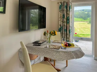 a table with a vase of flowers and a window at Alderneuk Lodge - Uk49923 in Dumfries