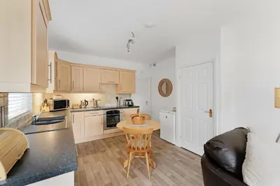 a kitchen with white cabinets and a table in it at 8 Harney Peak in Portinscale