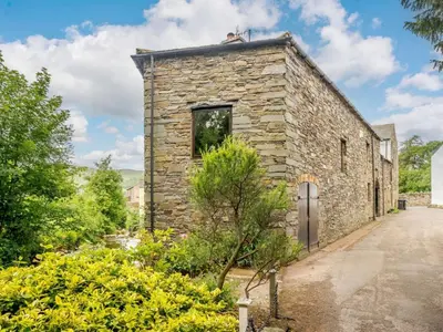 an old stone building with a door in a garden at 4 Bed in Cockermouth oc-sz098 in Lorton