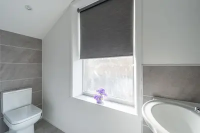 a bathroom with a toilet and a window with a purple flower at 5 Bed Workington House with Parking Near Station in Workington