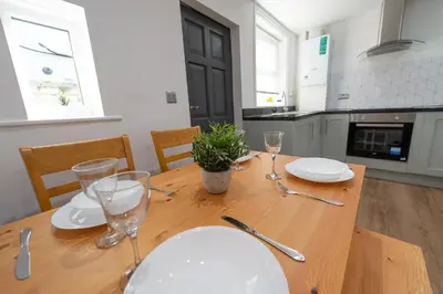 a dining room table with plates and glasses on it at 5 Bed Workington House with Parking Near Station in Workington