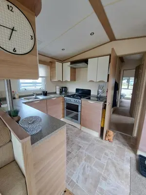 a kitchen with a large clock on the wall at Three lochs holiday park Loch view 123 in Balminnoch