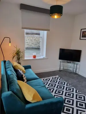 a blue couch in a living room with a television at No3 Spacious Apartment Cockermouth in Cockermouth