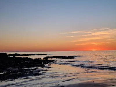 a sunset over the ocean with a beach at The Creamery High Harrington in Harrington