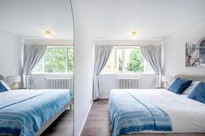 two beds in a room with two windows at Cozy 2 bedroom London Flat in Heart of Pimlico in Moffat