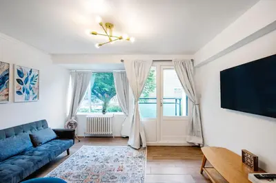 a living room with a blue couch and a tv at Cozy 2 bedroom London Flat in Heart of Pimlico in Moffat