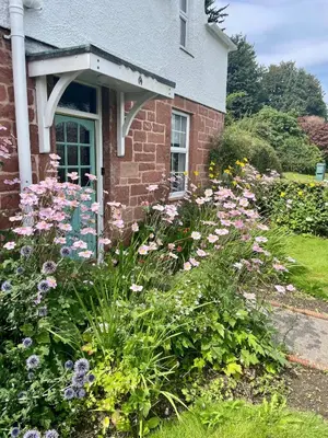 a garden of flowers in front of a house at Relax by the River, at Millgreen House in Dumfries