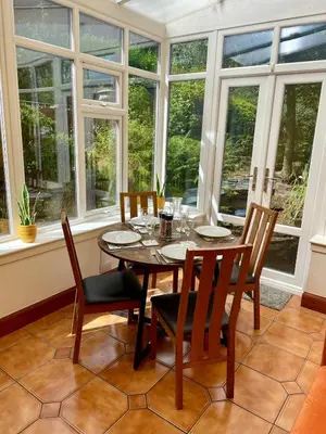 a dining room with a table and chairs and windows at Relax by the River, at Millgreen House in Dumfries