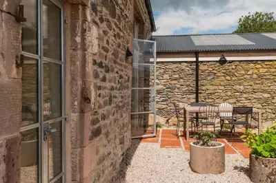 a stone building with a patio with a table and chairs at Swallow Barn at Greenclose Farm in Penrith