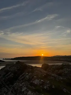 a sunset over a body of water with the sun setting at 87 Loch Murray in Creetown