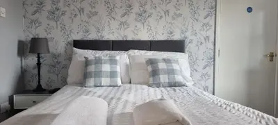 a bedroom with a white bed with blue and white wallpaper at Studio No5, Cockermouth The Lakes in Cockermouth
