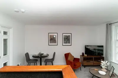 a living room with a table and a tv at Lovely 1 Bed Harbour-side Apartment - Sea Views in Whitehaven